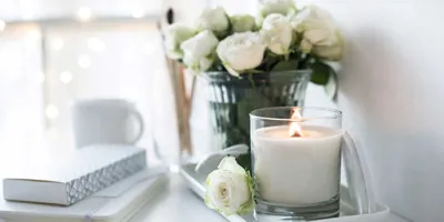A hand-made candle and bouquet of roses on a table