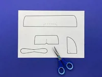 The printed template on a blue surface with a blue pair of child-friendly scissors.