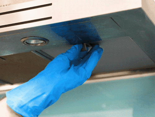 Hands in rubber gloves removing the cooker hood filter