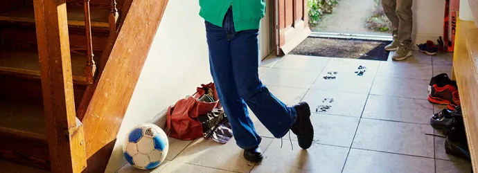 Young girl entering through the door of the house and making a mess on the floor with her grandmother watching her.
