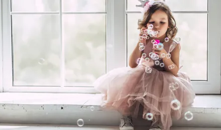 A little girl in a princess costume blowing bubbles