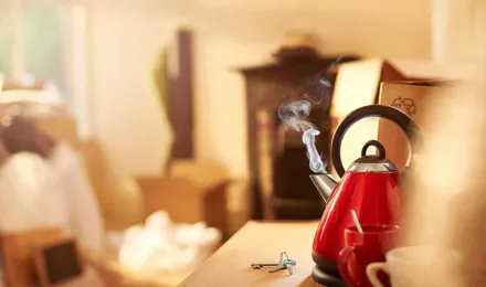 A red clean kettle boiling on the kitchen counter