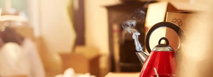 A red clean kettle boiling on the kitchen counter