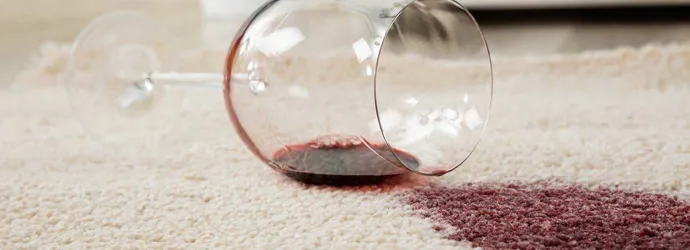Wijnglas omgevallen op een crème tapijt vormt een wijnvlek
