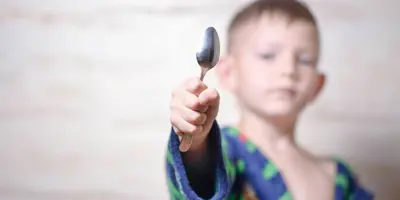 Ein Junge hält einen silbernen Löffel