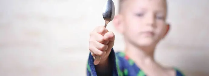 Ein Junge hält einen silbernen Löffel