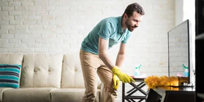 Ein Mann reinigt ein Haus durch Staubwischen