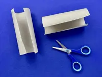 Two halves of cardboard tubes have been cut lengthwise and are on a blue table next to open scissors.