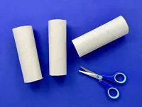 On a blue table are open, blue-handled scissors with three of the four halves of cardboard tubes.