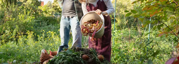 A person watches a girl empty out a bucket of vegetable scraps, demonstrating the difference between compostable and biodegradable