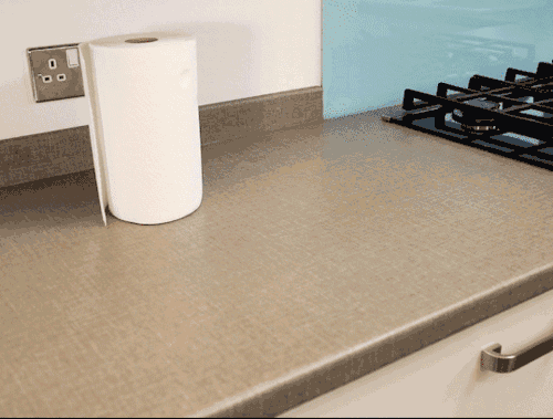 Gloves, white vinegar, bicarbonate of soda, hot soapy water, soft brush and kitchen towel lined up on a kitchen counter