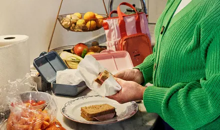 Eine Frau bereitet in der Küche Sandwiches für eine Schulbrotdose vor.
