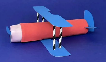A cardboard airplane made out of a paper tube, cardboard, straws, and other recycled materials.